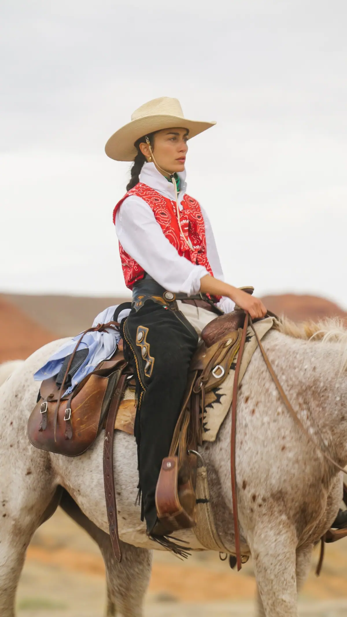 A rider on an Appaloosa below the red hills of Paintrock Canyon Ranch, Wyoming