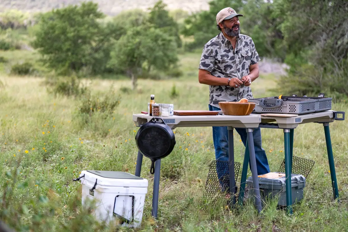Josh Crumpton cooking wild game at an outdoor kitchen in the Texas Hill Country