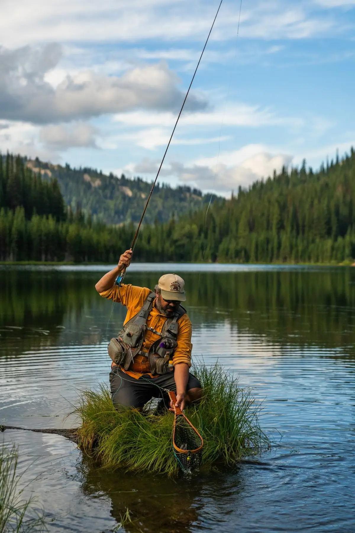 Josh Crumpton landing a trout on a mountain lake