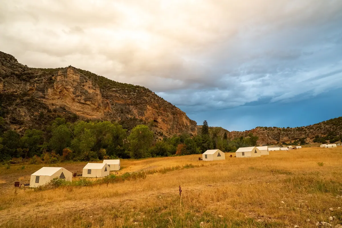 Safari tents at the mouth of Paintrock Canyon, Wyoming, under a storm sky
